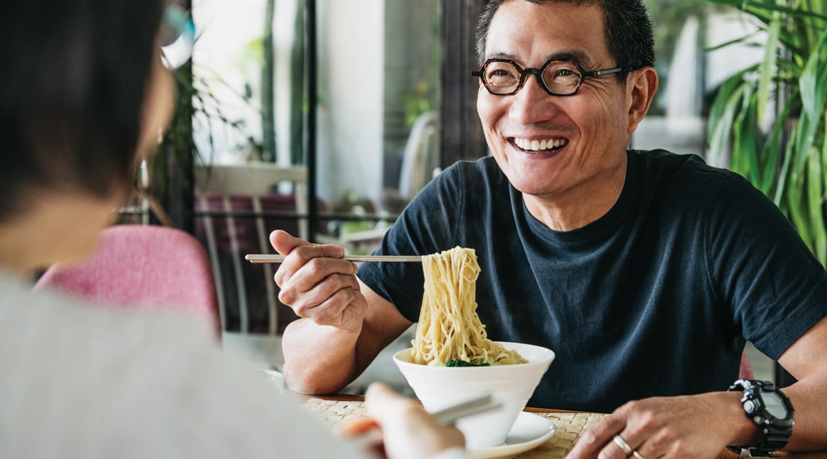 Man in his 50s talking to woman and smiling, freshly made Chinese food, noodle soup, lunch, relaxation