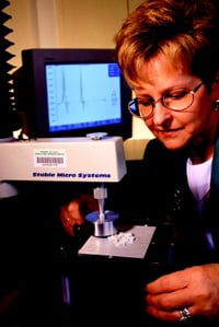 Food scientist uses a computerized texture analyzer that translates compression analysis data for rice samples into force compression curves shown on the monitor.