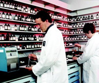 Scott Gilbertson, Junior Flavor Chemist at Wixon, Inc., measures the flash point of a flavor using an automatic flashpoint meter, while Mindy Edwards, Certified Flavor Chemist, weighs out flavor chemicals to create a flavor.