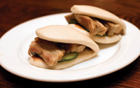 Menu items served at Momofuku Ssam, including this steamed bun with Berkshire pork, pickled Kirby cucumbers, hoisin, and scallion, steer clear of traditional approaches to food preparation. 