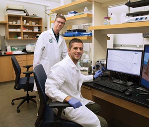 Chad Hancock (standing) reviews the results of an experiment performed by BYU student Chandler Eyre (seated). 