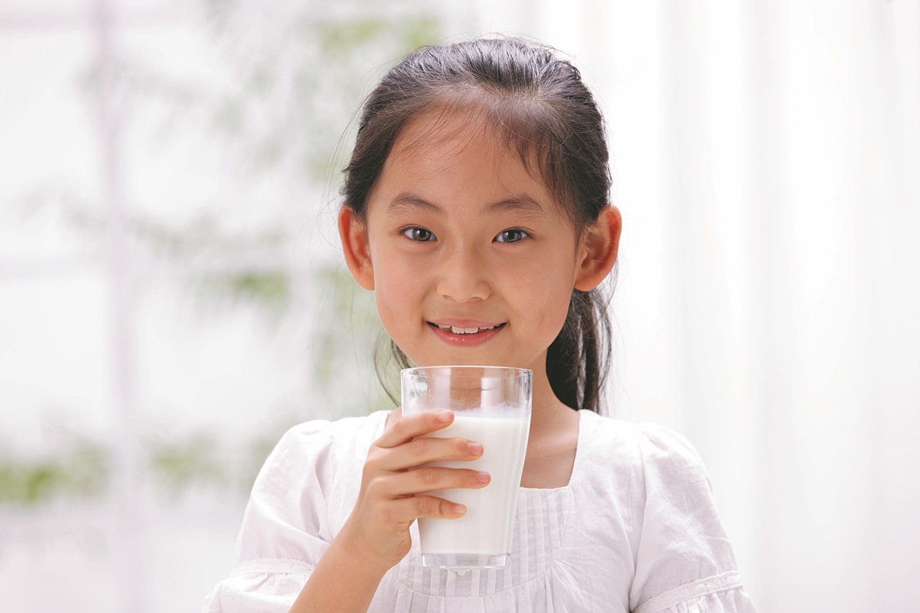 Young girl drinking glass of dairy