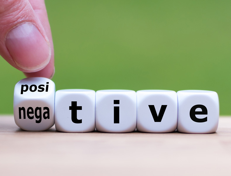 Hand turns a dice and changes the expression "negative" to "positive".