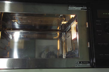 Fig.1—Interior of a combination microwave–infrared oven (AdvantiumTM from General Electric, Louisville, Ky). The inside of the oven has dimensions 0.470 m x 0.356 m x 0.215 m (height). The infrared (halogen) sources are at the top (as shown in the middle) and at the bottom (not shown). The microwaves are introduced from the side as shown.
