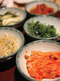Side dishes served at a Korean BBQ dinner include various vegetables as well as kimchi (front), which is a dish of fermented vegetables (in this case cabbage) and seasonings.