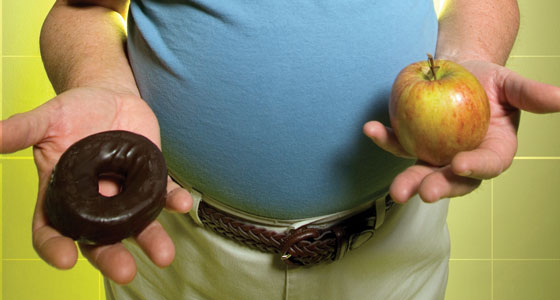 Man holding donut and apple.