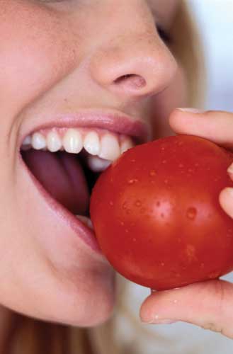 Woman eating a tomato.