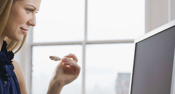 Woman eating snack at computer