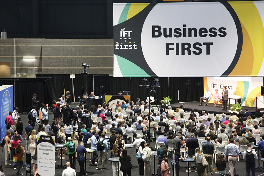 The Business FIRST stage of panelists and presenters with a large crowd in attendance