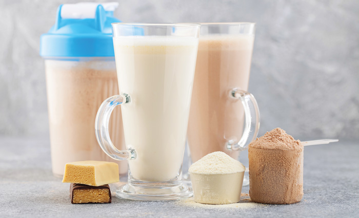 Sports nutrition, fitness diet and food concept - glass, protein shake bottle, powder and bars