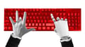 Composition of human and robotic hands typing on red keyboard symbolizing digital cooperation.