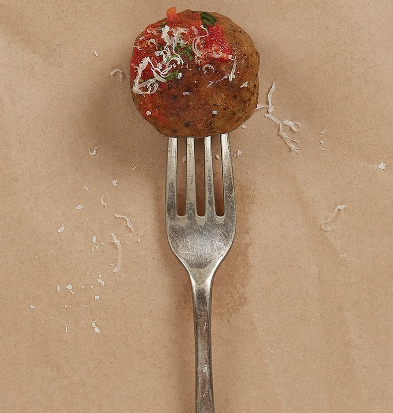 Fork through an Ivy Farm meatball with grated cheese, greens, and tomato on top