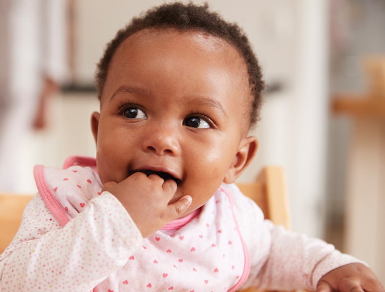 Cute Baby Girl Wearing Bib Sitting In High Chair