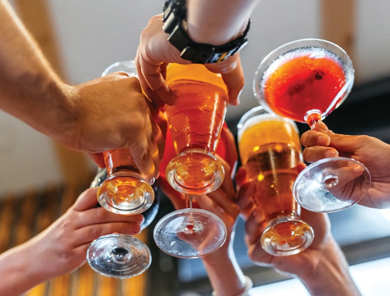 Young group of friends relaxing in a bar, cheering with their drinks.