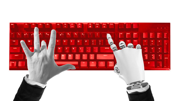 Composition of human and robotic hands typing on red keyboard symbolizing digital cooperation.