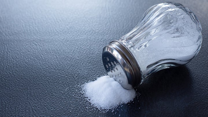 Glass salt shaker on table background.