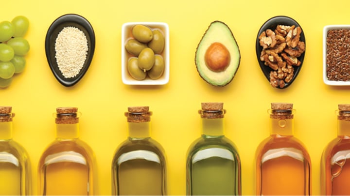 Vegetable fats. Different oils in glass bottles and ingredients on yellow table