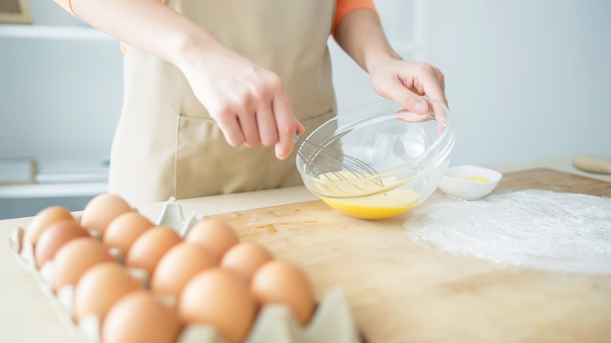 Person preparing food by beating eggs in a bowl