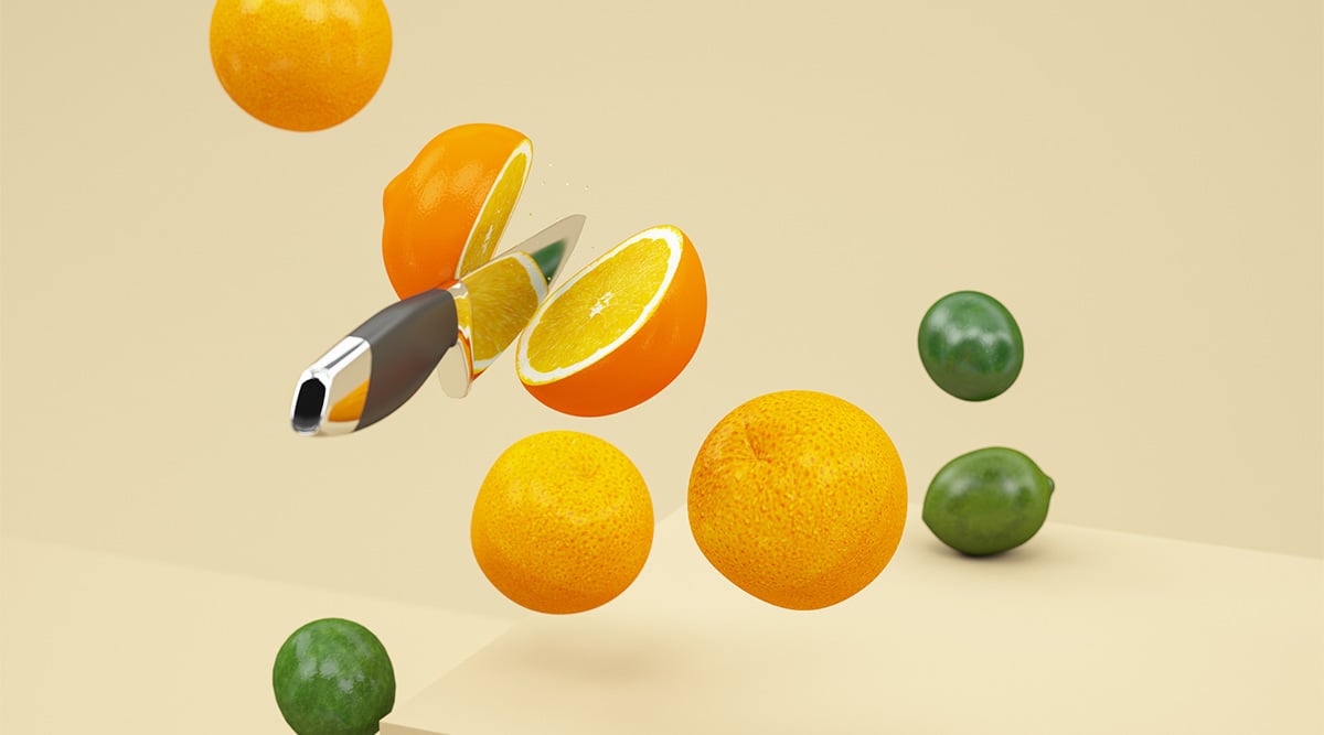 Floating oranges and limes with a knife slicing through an orange.