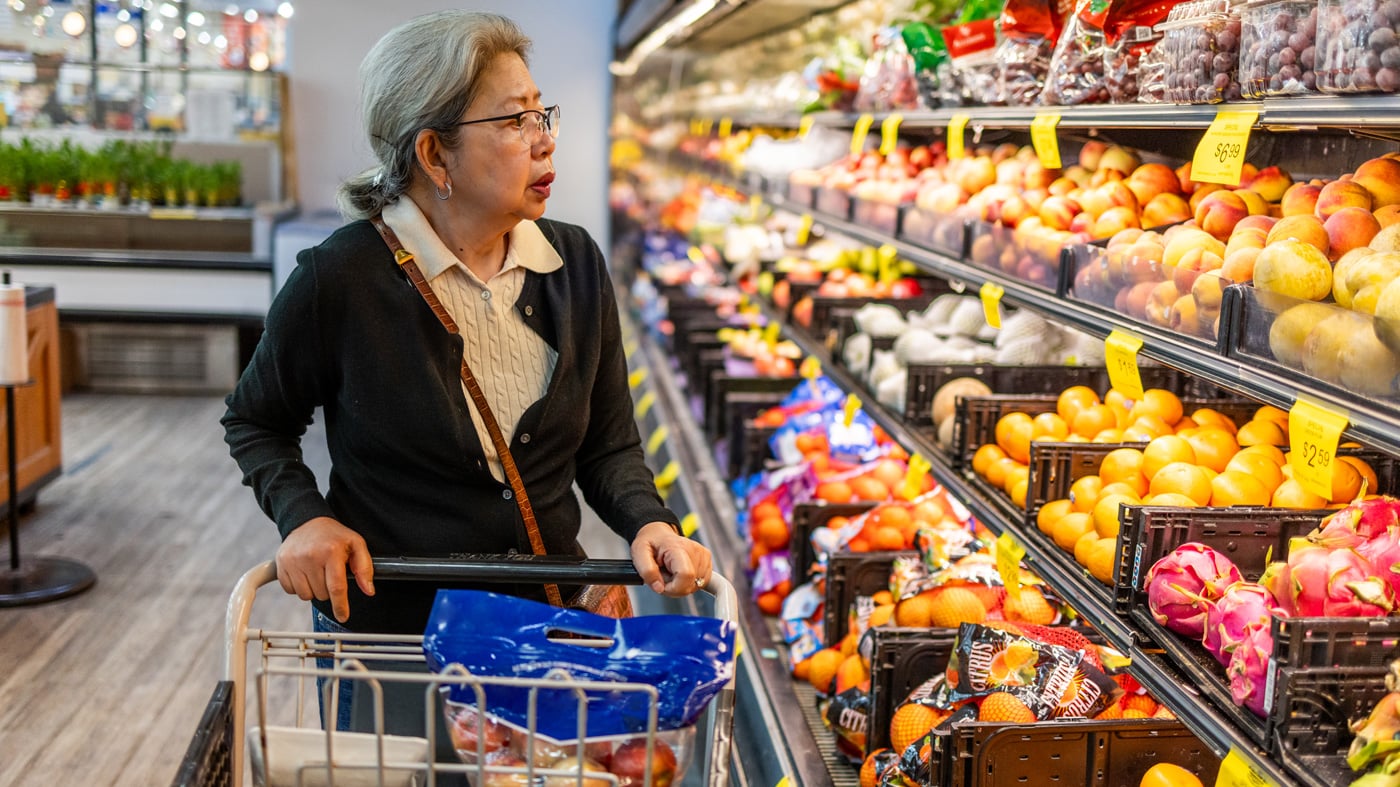 Asian-American senior woman shopping for food at a local grocery store, coping with high prices as inflation continues to push deeper into fixed incomes.