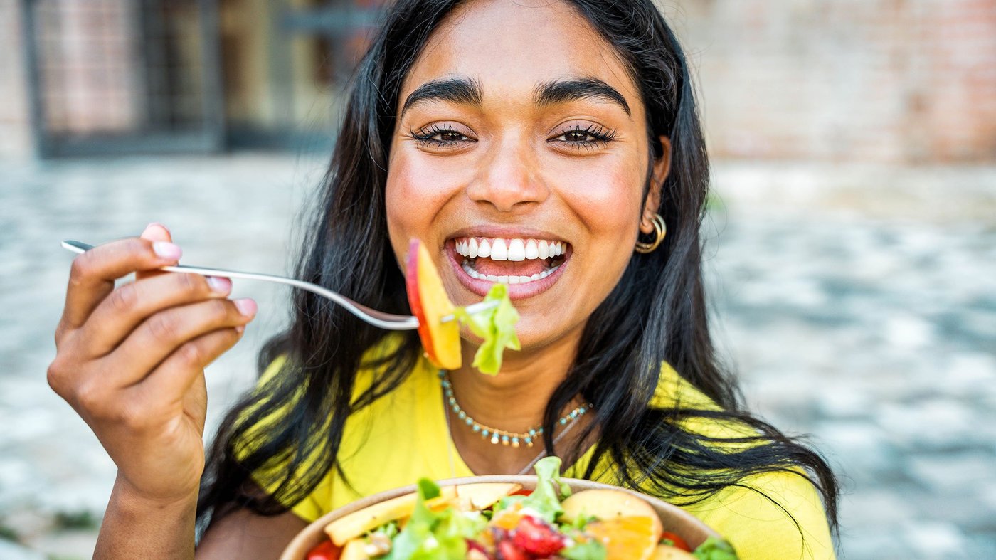 young woman eating salad outside