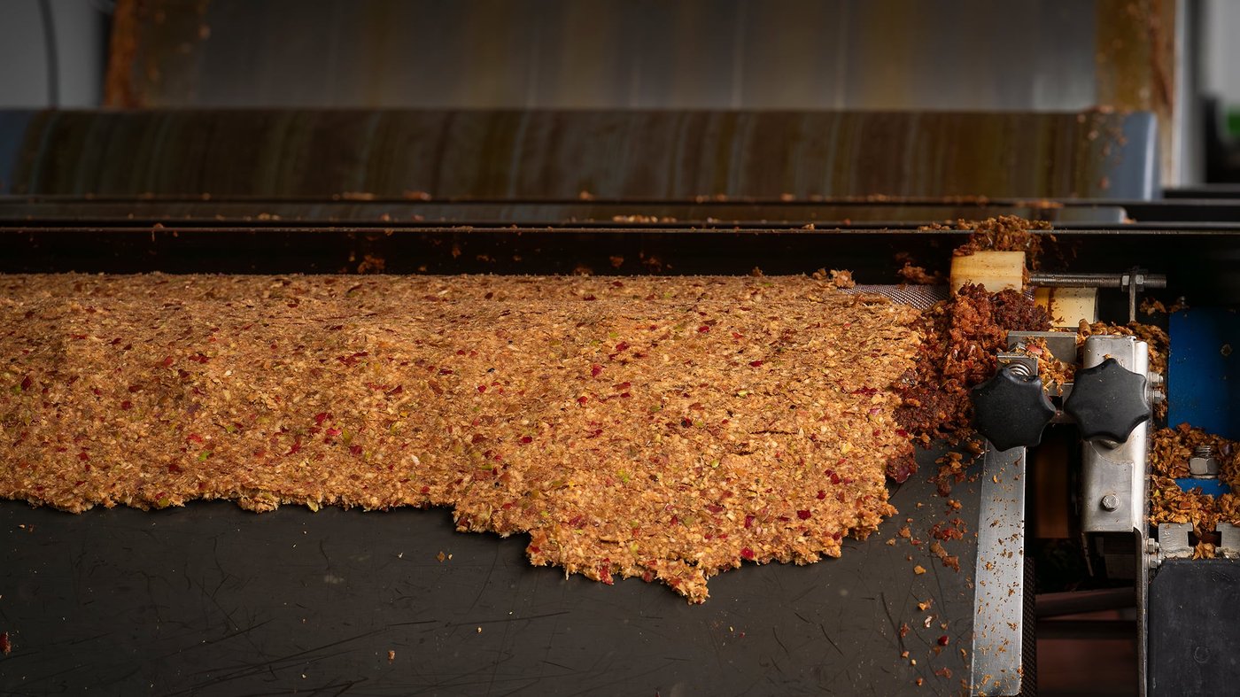 Apple pomace spread on an industrial press belt during cider manufacturing.