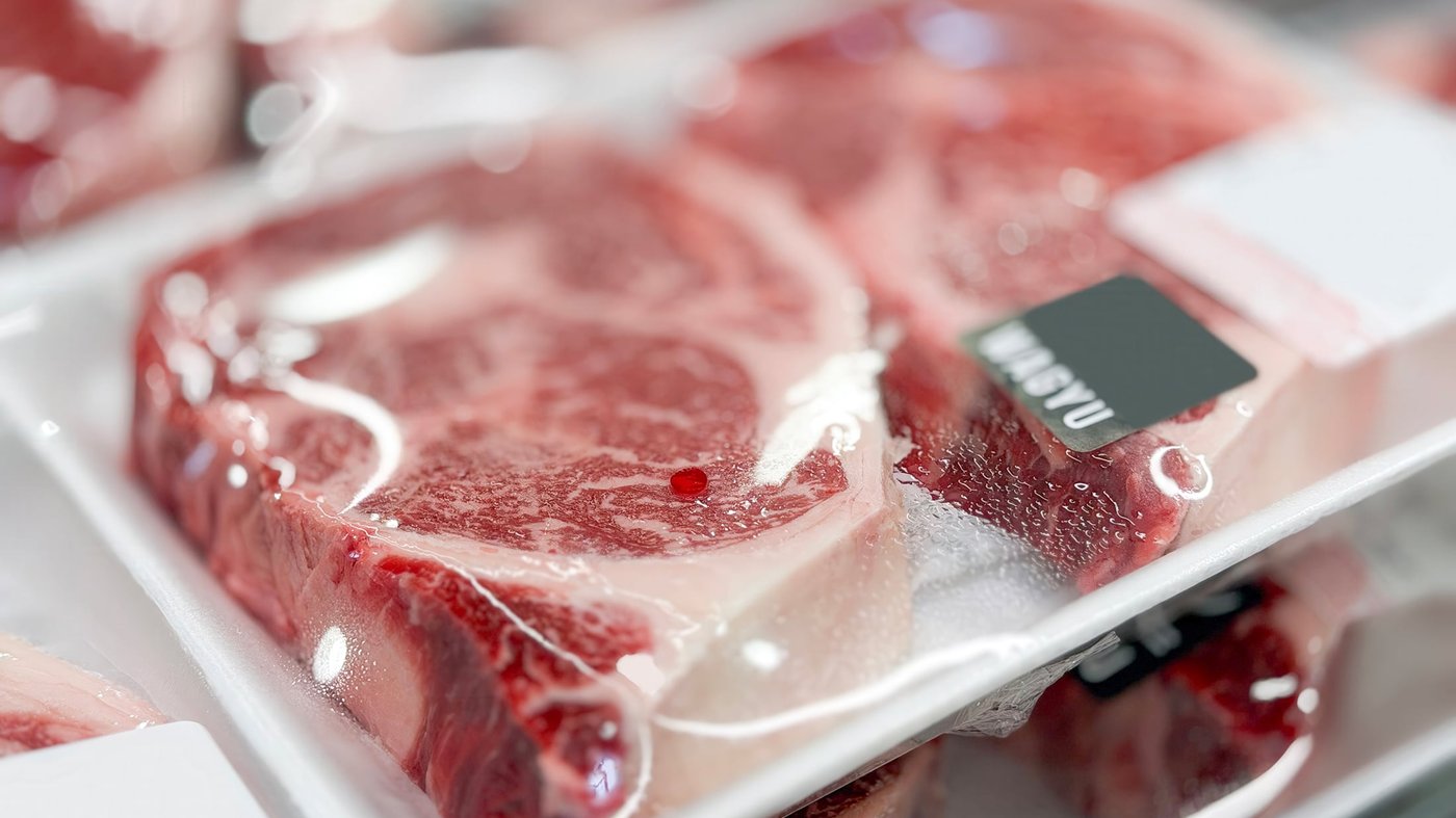 Wagyu-style beef steaks sit inside a white foam tray, tightly wrapped in clear plastic packaging