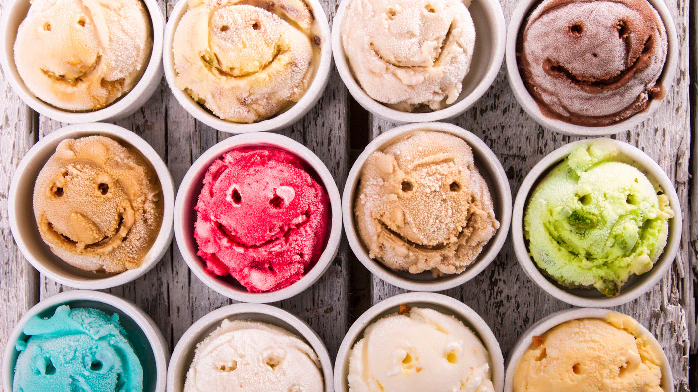 Selection of gourmet flavours of Italian ice cream in vibrant colors served on an old rustic wooden table in an ice cream parlor, overhead view