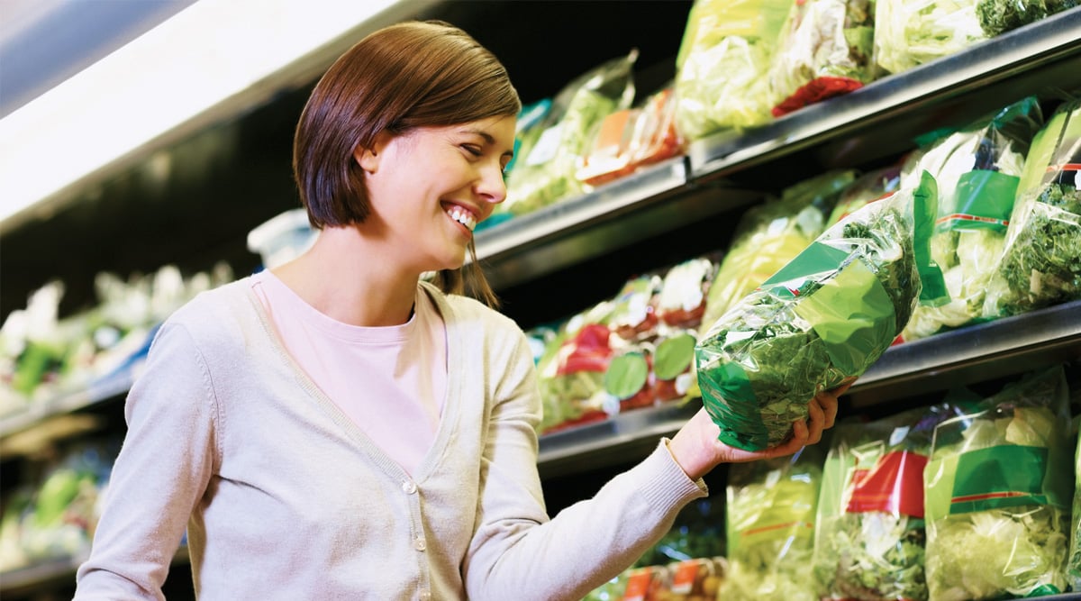appy woman purchase a packet of vegetables from a supermarket