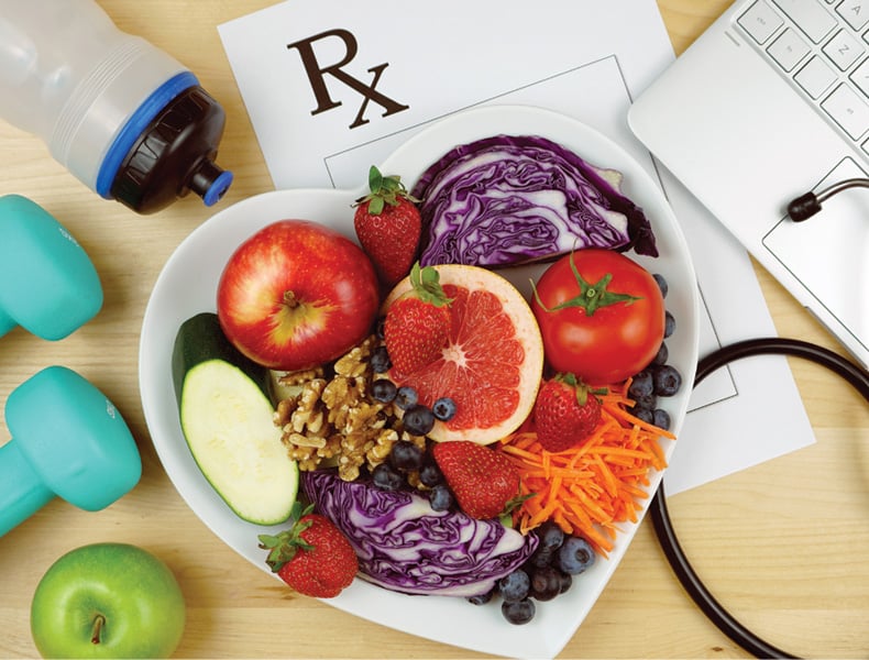 Prescription for good health overhead with stethoscope, healthy fresh food and exercise equipment.