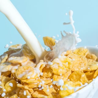Milk stream pouring into a bowl with сornflakes