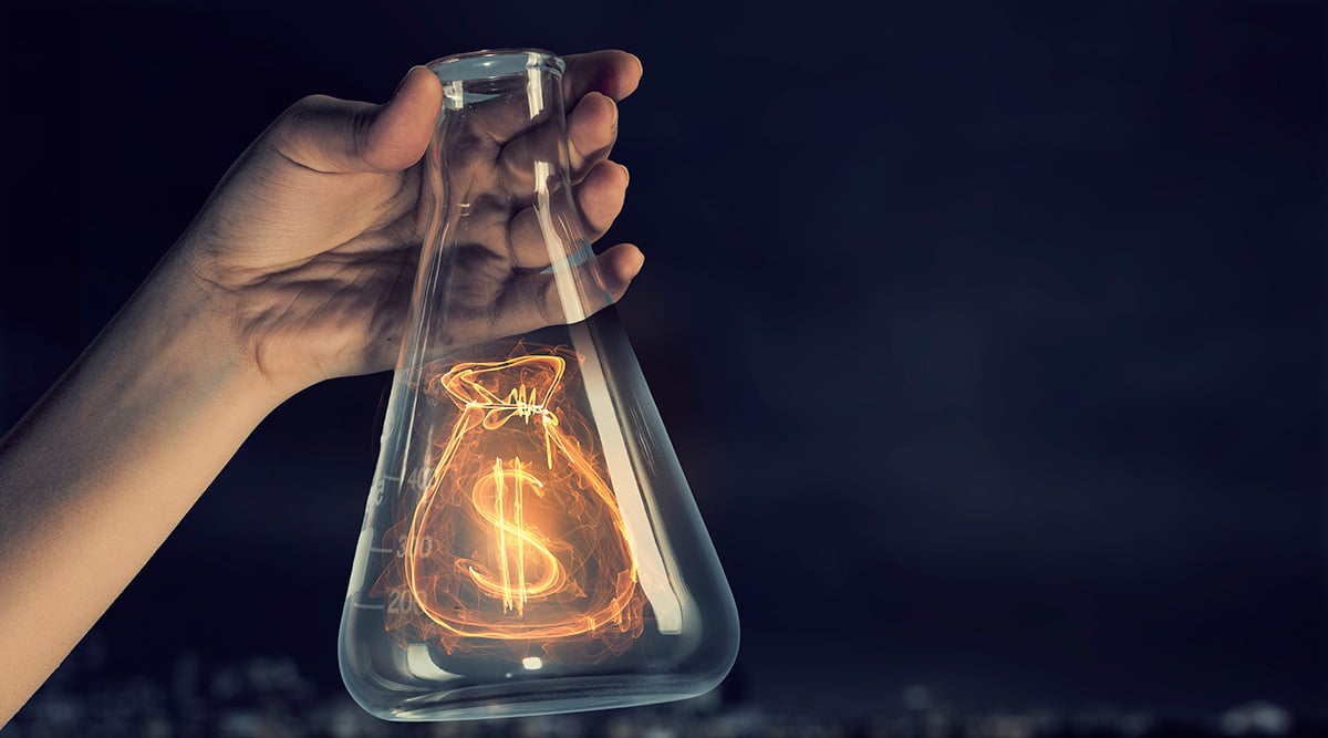 Hand holding an Erlenmeyer flask with an illuminated money bag inside