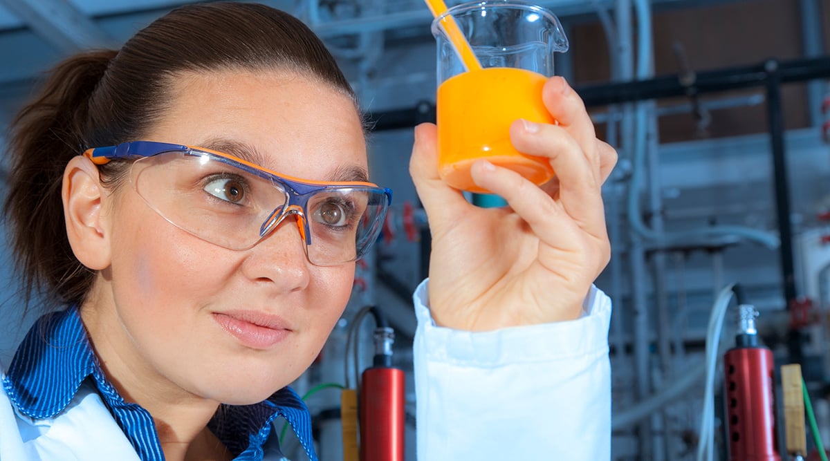 woman scientist examining bright orange liquid