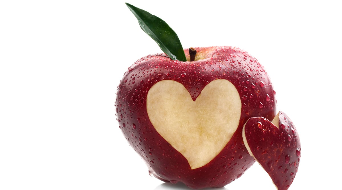 A red apple with a heart cut out of it.