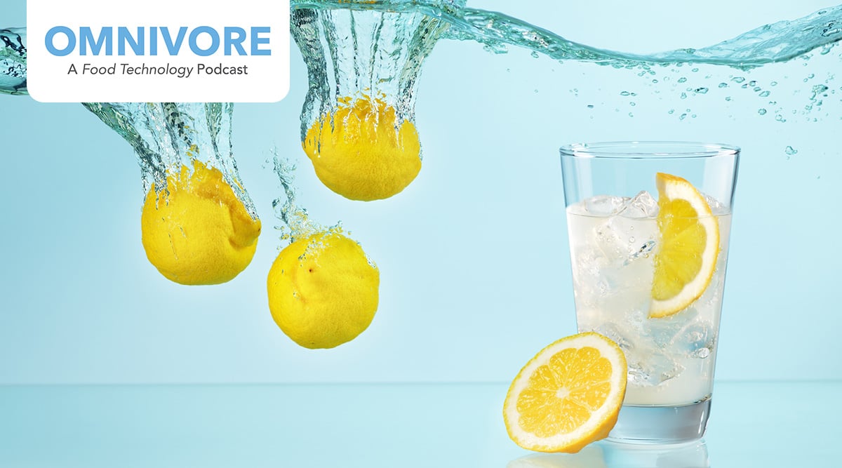 Three whole lemons under water and a glass of water with a lemon wedge.
