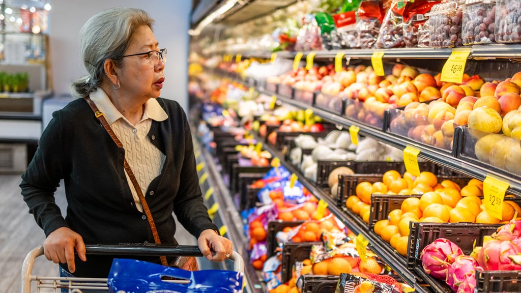 Asian-American senior woman shopping for food at a local grocery store, coping with high prices as inflation continues to push deeper into fixed incomes.