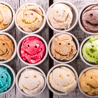 Selection of gourmet flavours of Italian ice cream in vibrant colors served on an old rustic wooden table in an ice cream parlor, overhead view