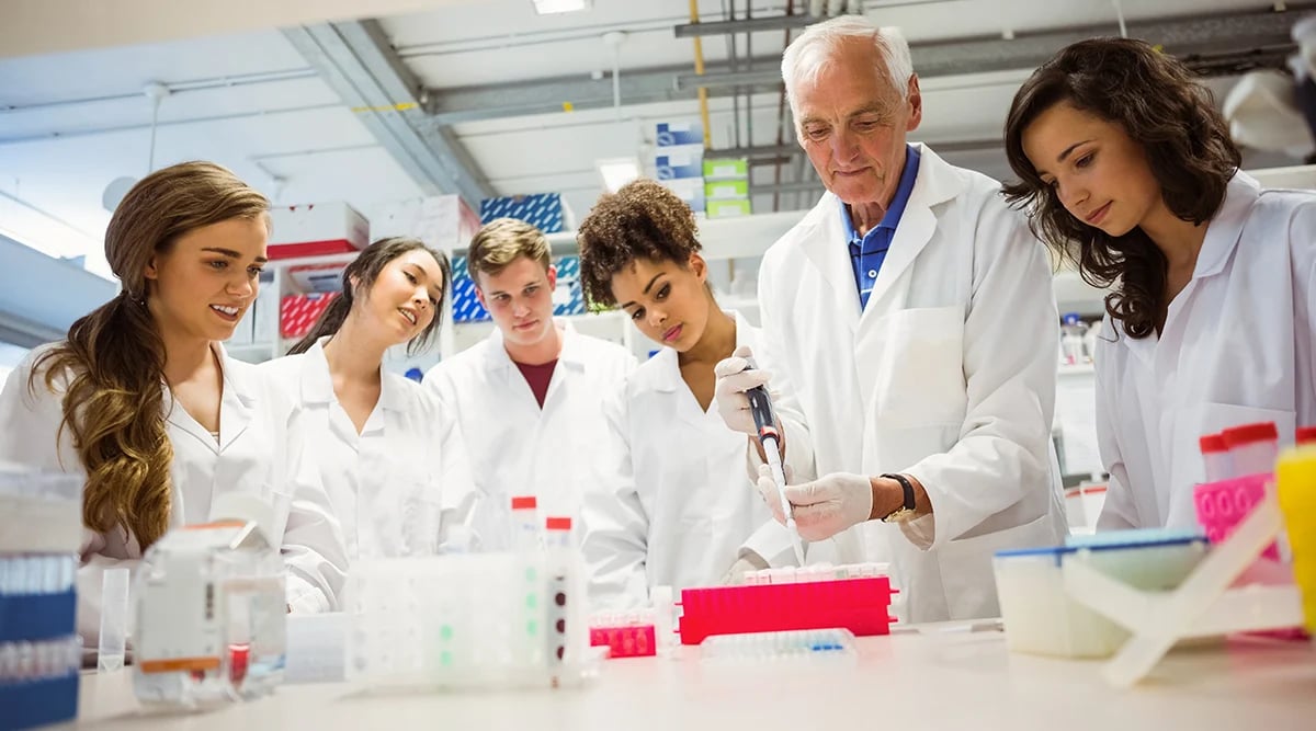 Students in a lab watching their instructor demo an experiment.