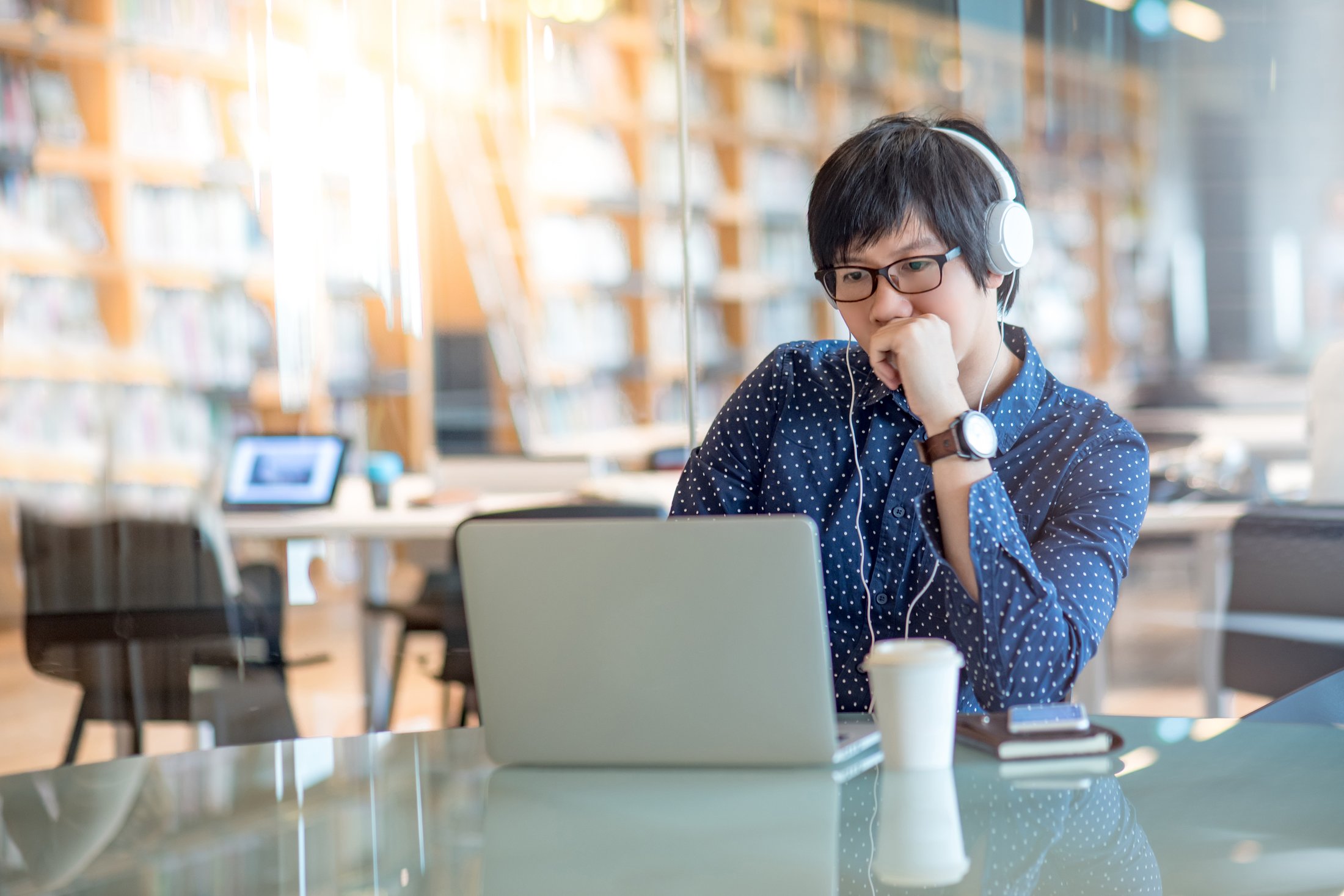 Man sitting at table looking at laptop