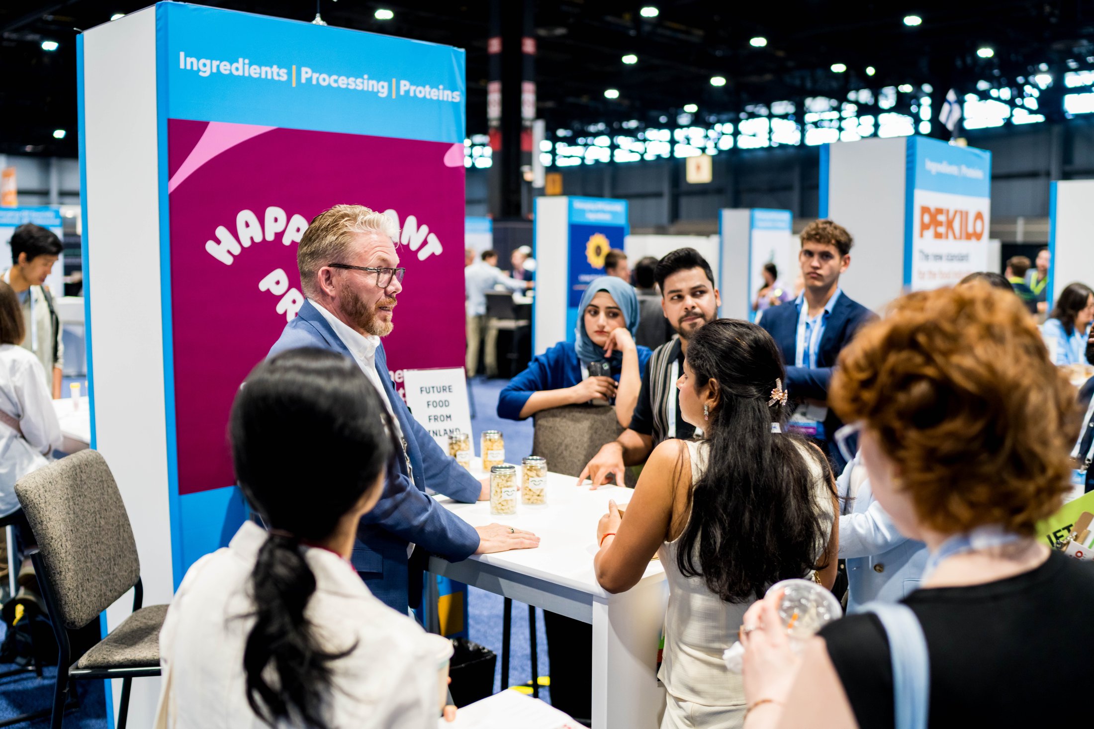 An exhibitor speaking in front of a crowd of people around their booth at IFT FIRST.