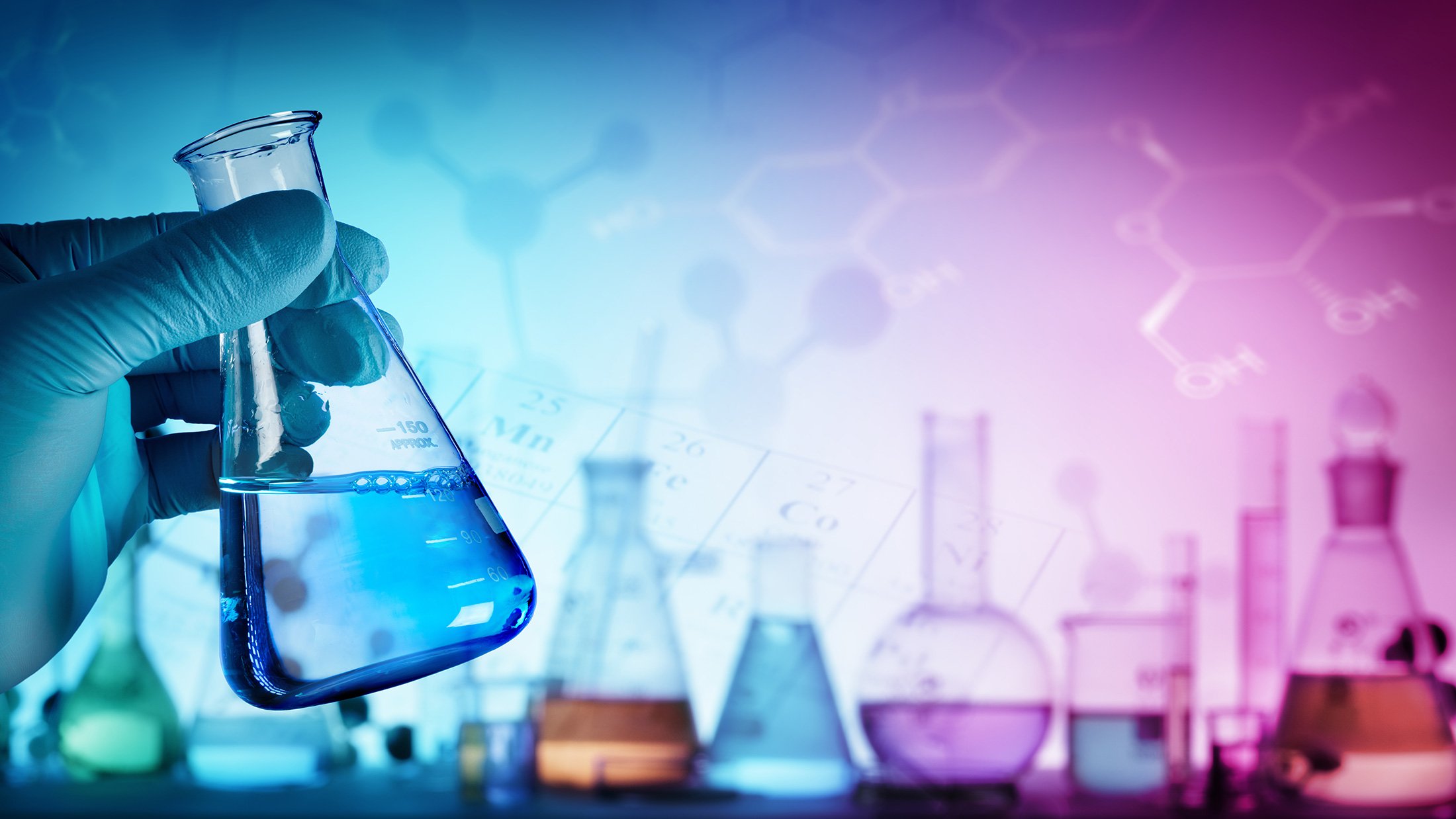 Gloved hand holding a beaker and colorful lab equipment in background