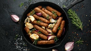 Rosemary and onion vegetarian vegan sausages oven baked in cast iron skillet frying pan.