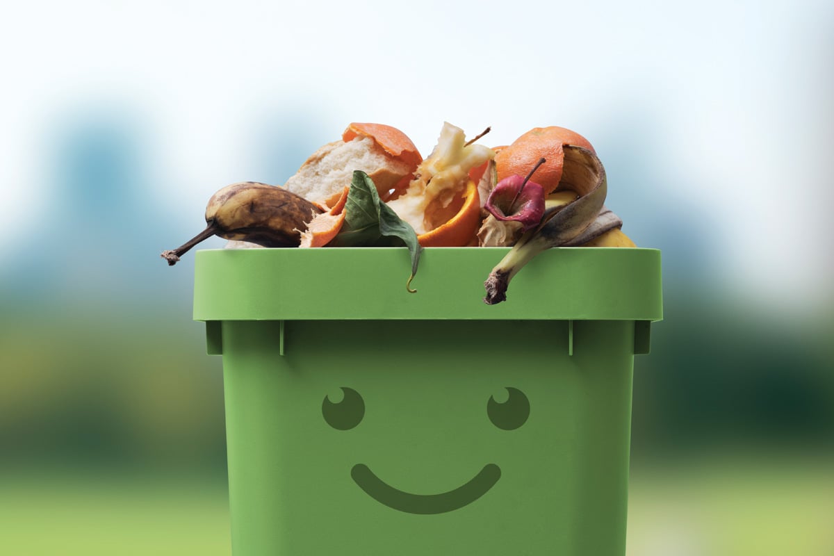 Smiling cute garbage bin character full of organic biodegradable waste.