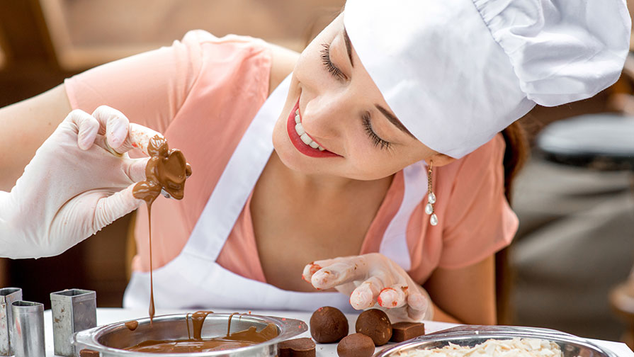 Omnivore Podcast Episode 10 a smiling baker dipping a piece of dough in chocolate