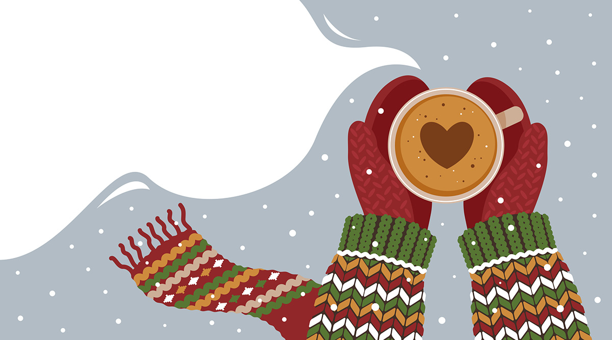 Person wearing a holiday sweater, scarf, and mittens holding hot cocoa with a heart out in the snow.