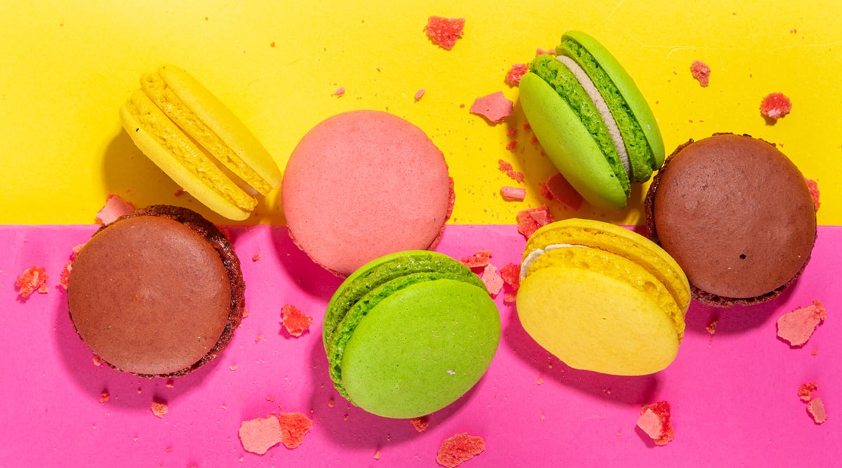 Colorful macarons against a pink and yellow background.