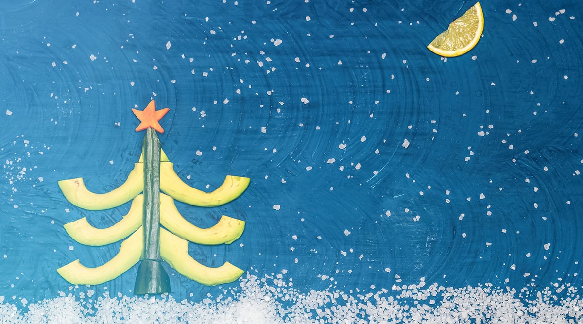 A Christmas tree against a blue snowy backdrop and a lemon slice in the sky