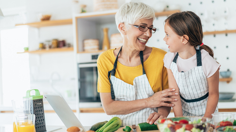 Omnivore Podcast Episode 8 a woman and a child in a kitchen smiling at each other while making a nutritious meal.