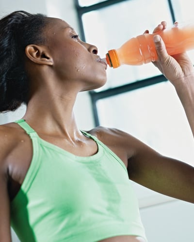 Young african american woman in sportswear with energy drink in gym.