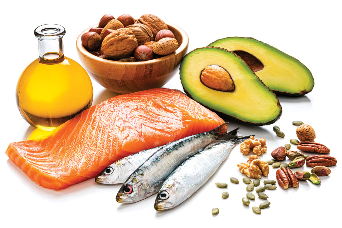 Healthy eating for well balanced diet and heart care: close up view of a group of food rich in healthy fats including salmon, sardines, avocado, extra virgin olive oil, nuts and seeds like walnut, almonds, pecan, hazelnuts, pistachio and pumpkin seeds.